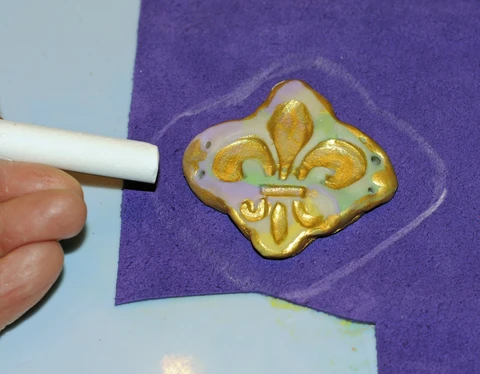 sewing the air dry clay jewelry piece onto felt